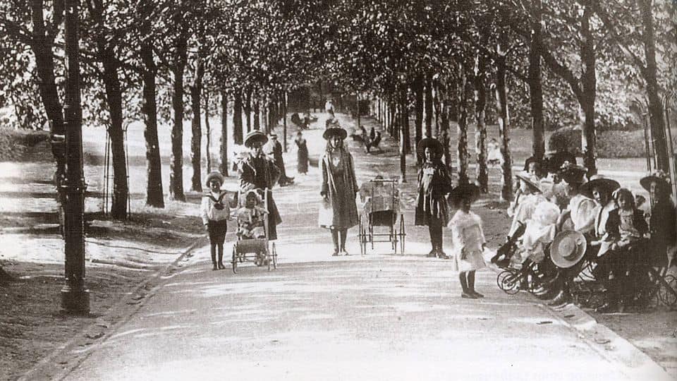 Historic photo of the Vines lined with trees and featuring mothers or nannies and several babies and young children